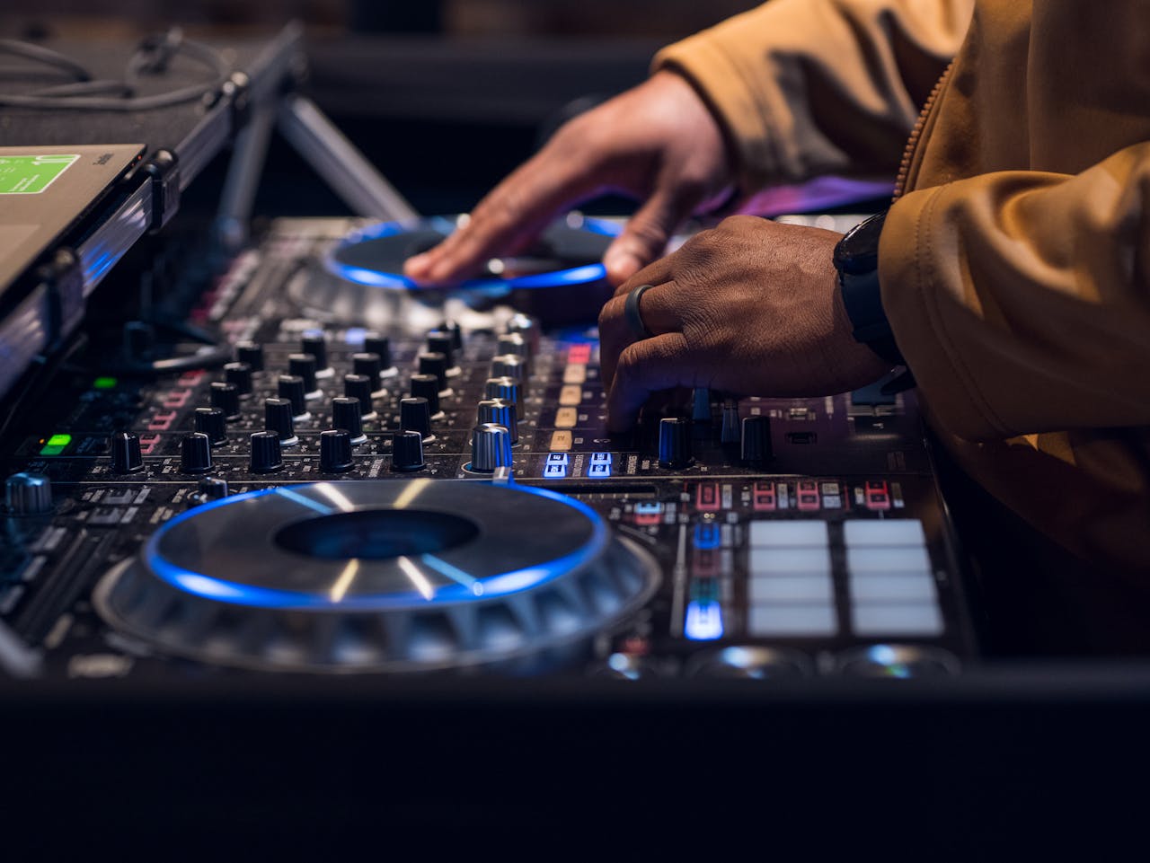 Professional DJ mixing music on a modern DJ controller with vibrant lights.