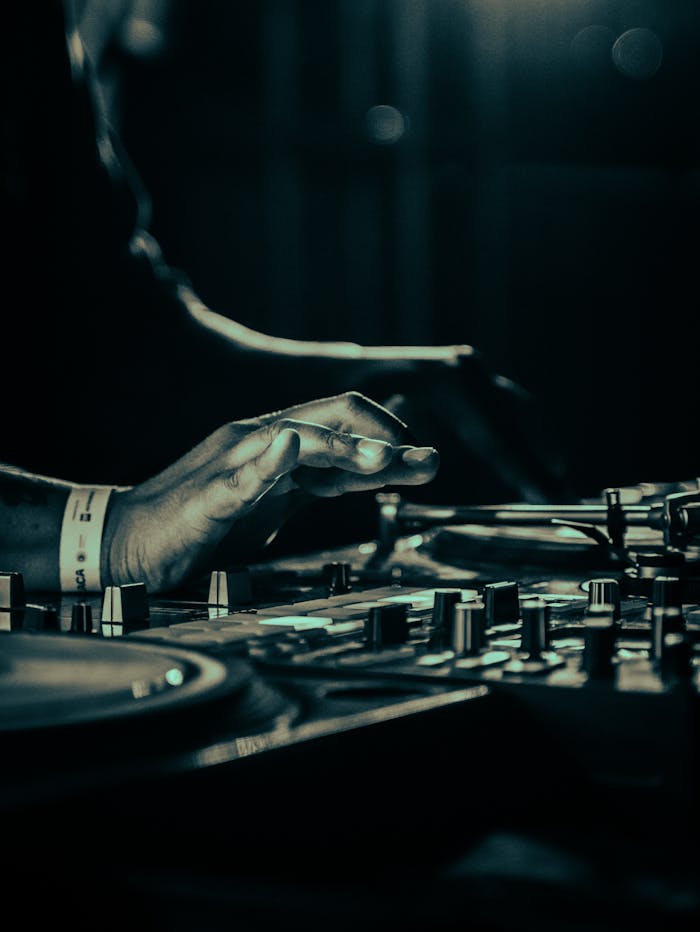 Close-up of a DJ mixing tracks in a nightclub setting with blue lighting for a moody atmosphere.